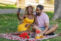 A Happy Couple of African-American Ethnicity is on a Picnic in a Nature. They are Enjoying in Delici...