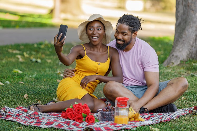 A Happy Couple of African-American Ethnicity is on a Picnic in a Nature. They are Enjoying in Delici...