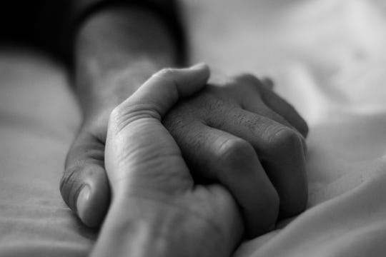 couple holding hands in bed 