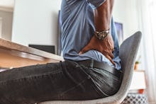 Businessman working sitting at desk feels unhealthy suffers from lower back pain. Damage of interver...