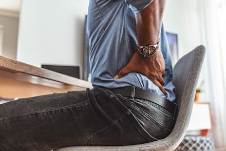 Businessman working sitting at desk feels unhealthy suffers from lower back pain. Damage of interver...
