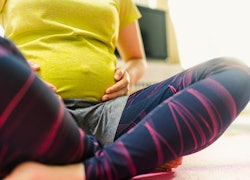 A young pregnant woman is doing breathing and relaxation exercise at home.