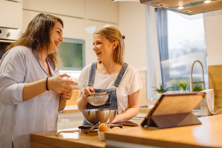 Two happy friends bake a dessert in the kitchen.