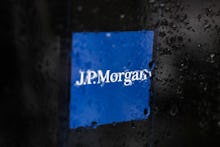 JP Morgan logo displayed on a phone screen is seen through raindrops on the window in this illustrat...