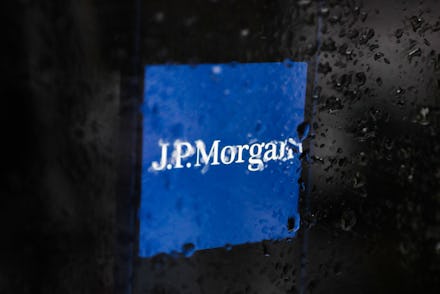 JP Morgan logo displayed on a phone screen is seen through raindrops on the window in this illustrat...