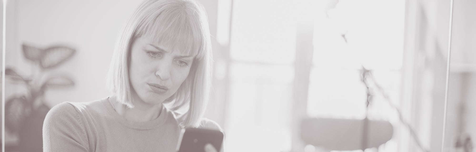 A businesswoman is reading an e-mail from a coworker. She's feeling surprised in a negative way.