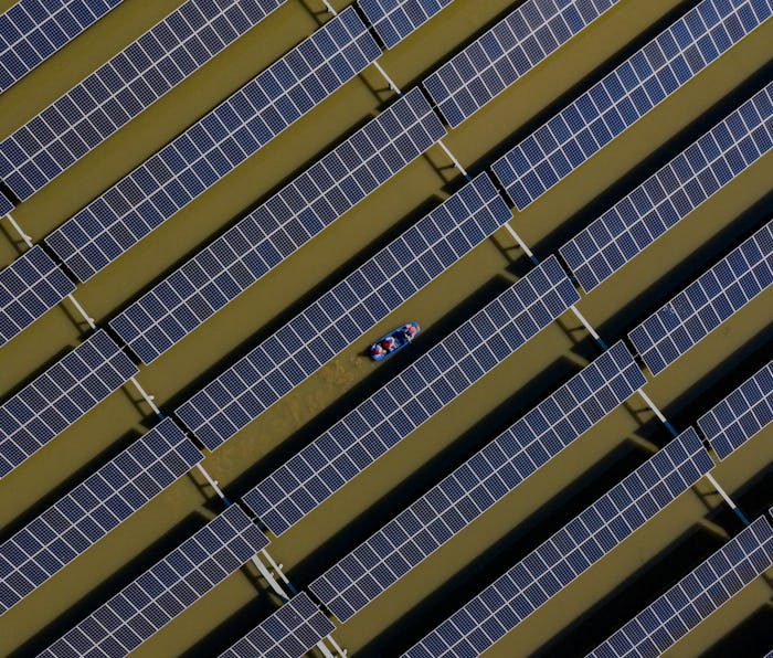 HAI AN, CHINA - APRIL 06: Workers carry out maintenance on solar panels installed atop a fish pond a...
