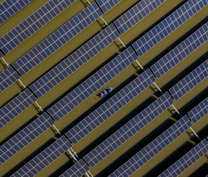 HAI AN, CHINA - APRIL 06: Workers carry out maintenance on solar panels installed atop a fish pond a...