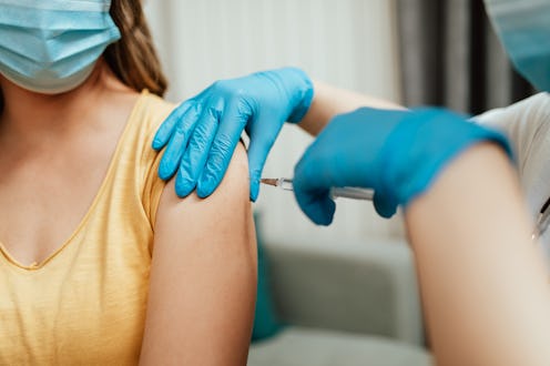 Female doctor vaccinating middle age female patient at home. People are wondering if the COVID vacci...