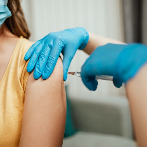 Female doctor vaccinating middle age female patient at home. People are wondering if the COVID vacci...