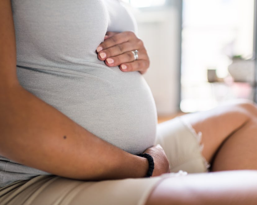 Pregnant woman embracing her pregnant belly.