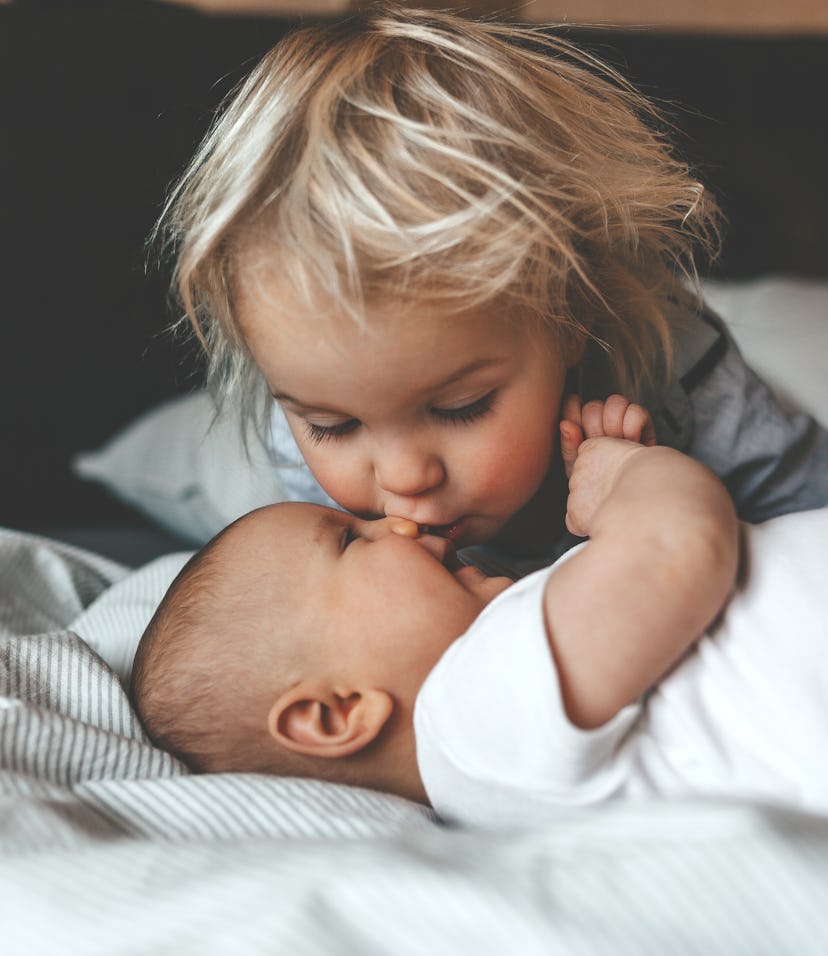 Little brother hugging his newborn sister. Toddler kid meeting new sibling. Cute boy and new born ba...
