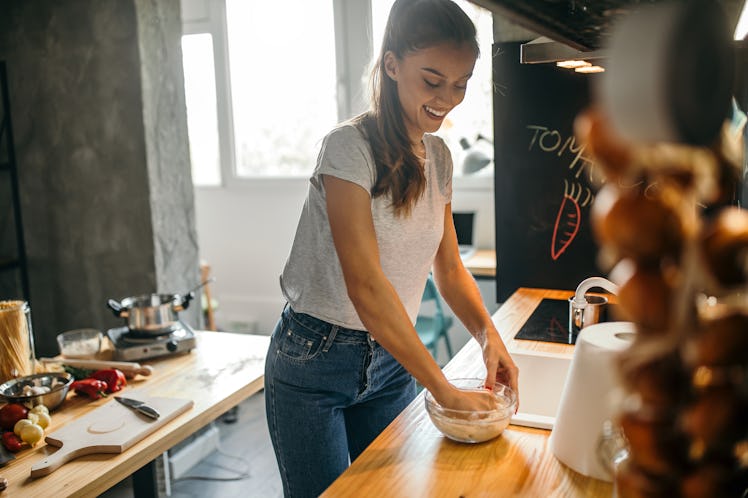 A woman makes pizza dough in her kitchen at home.
