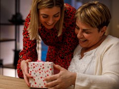 A woman gives her mom a gift box for Mother's Day. 