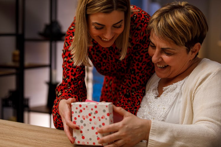 A woman gives her mom a gift box for Mother's Day.