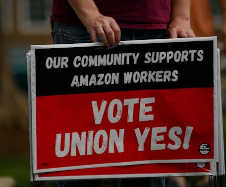 A person holds "Vote Union Yes!" signs during a protest in solidarity with Black Lives Matter, Stop ...