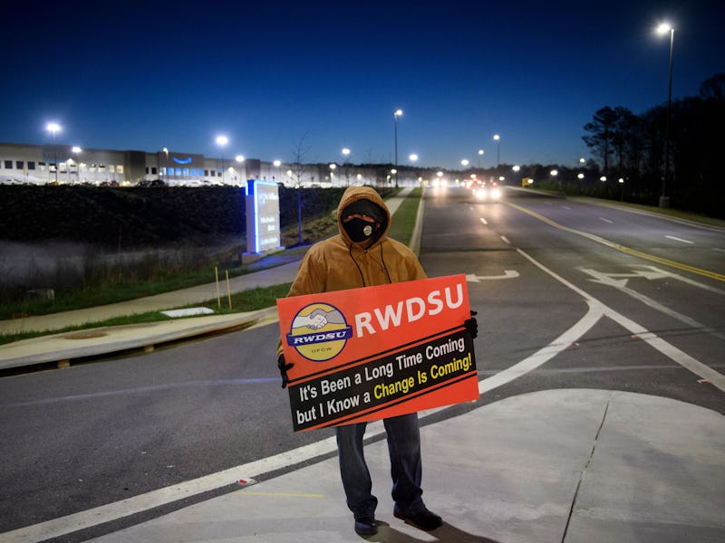 A union supporter stands before sunrise outside the Amazon.com, Inc. BHM1 fulfillment center on Marc...