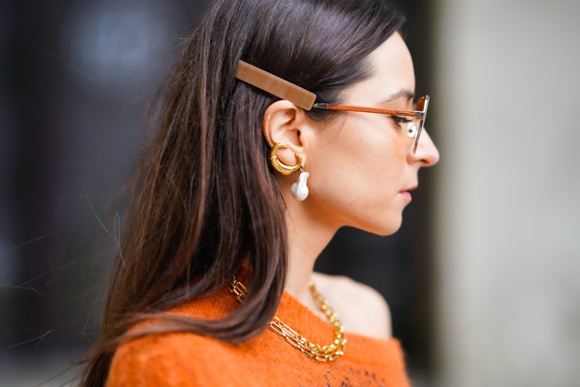 PARIS, FRANCE - OCTOBER 01: Julia Comil wears orange clear sunglasses, pearl earrings, a golden neck...