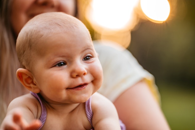 Cute baby girl smiling in her moms lap, baby girl names like mila