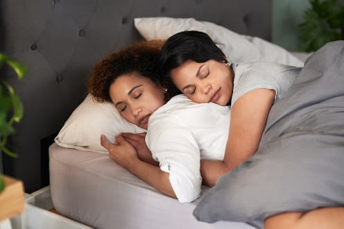 Two people sleep in a bed together, cuddling closely. Asexuality is an umbrella term that can mean a...