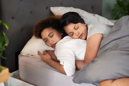 Two people sleep in a bed together, cuddling closely. Asexuality is an umbrella term that can mean a...