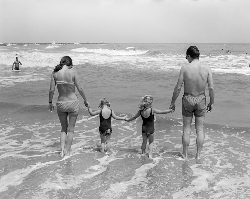 A 1970s family walking together on the beach.
