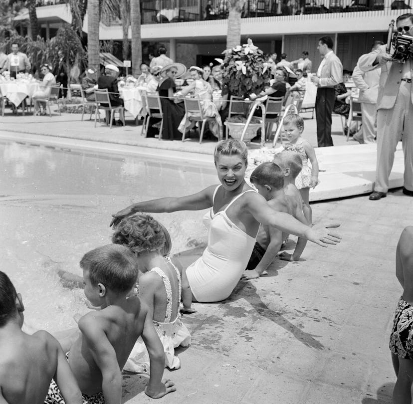 Actress Esther Williams sits pool side with children during the opening day of the Esther Williams S...