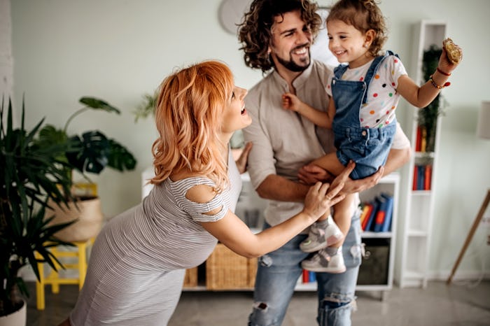 Pregnant woman, husband and daughter enjoy their house having fun