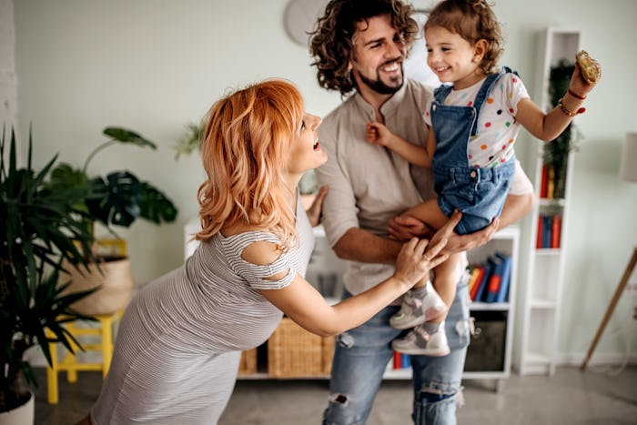 Pregnant woman, husband and daughter enjoy their house having fun