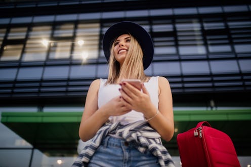 Woman tourist waiting on the street, texting on the phone, summer fashion style