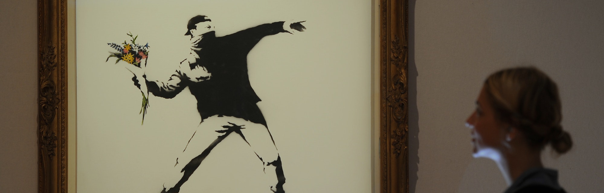 Bonhams assistant Bernice Robaglia views Banksy's 'Love is in the Air' which is expected to fetch 10...