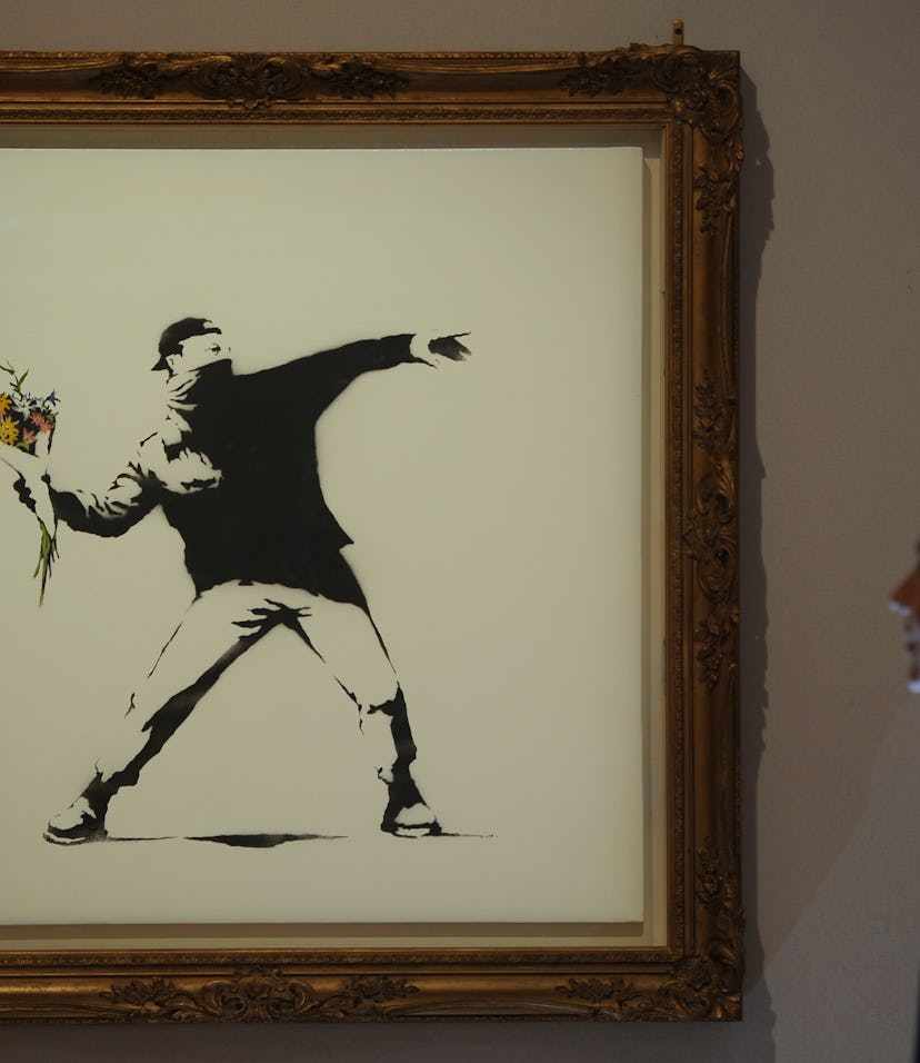 Bonhams assistant Bernice Robaglia views Banksy's 'Love is in the Air' which is expected to fetch 10...