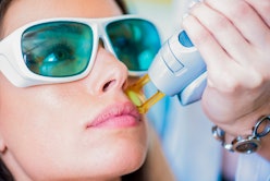 A young woman getting facial hair removed by a laser epilator in a cosmetic center.