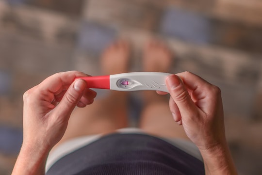 Woman holding a negative pregnancy test on a light background. Motherhood, pregnancy, the concept of...