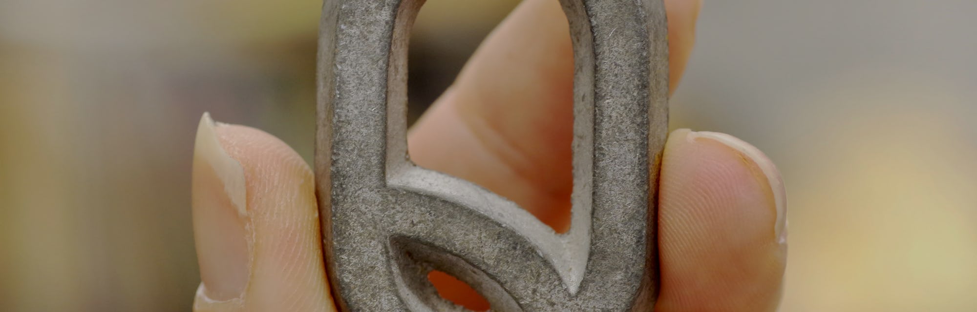 Caucasian female hand holding up a metal capital Q