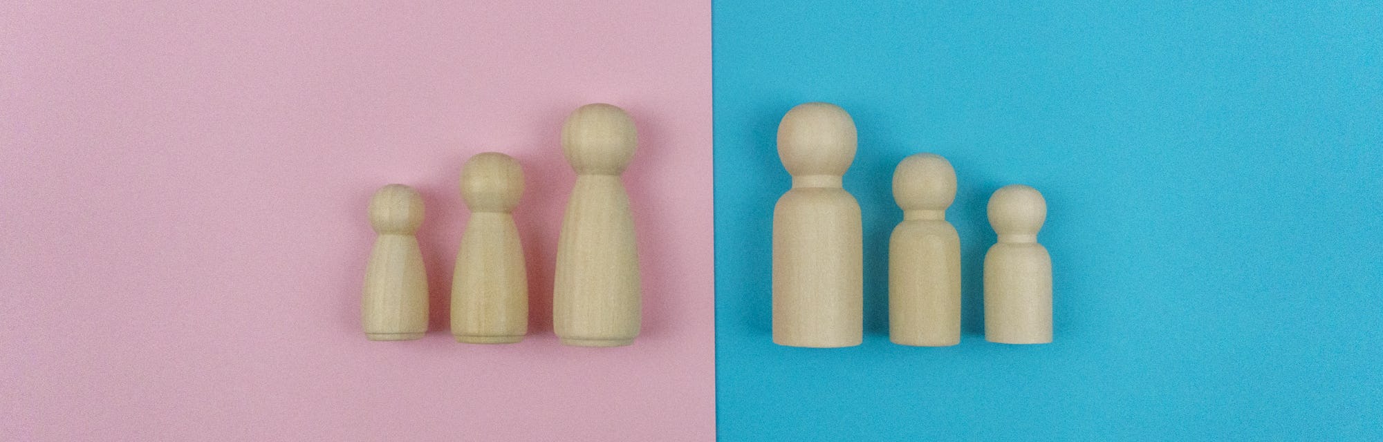 Still life image, Wooden figures family of four on Blue and Pink background.