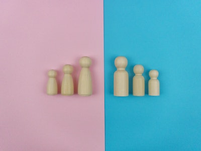 Still life image, Wooden figures family of four on Blue and Pink background.