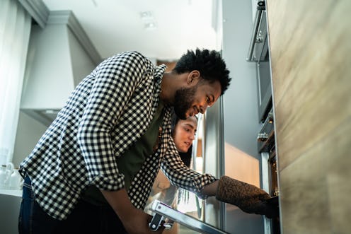 Couple looking bake food preparation into the oven at home