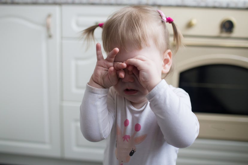 Toddler girl covered her eyes with her hands and crying
