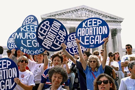 Pro-life and pro-choice demonstrators hold signs on the steps of the Supreme Court building  The pro...