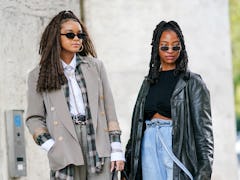 PARIS, FRANCE - OCTOBER 01: A guest (L) wears black sunglasses, a gold earring, a silver and gold rh...