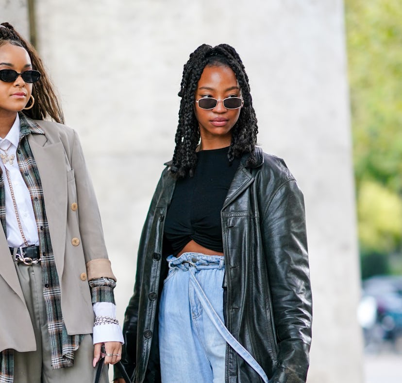 PARIS, FRANCE - OCTOBER 01: A guest (L) wears black sunglasses, a gold earring, a silver and gold rh...