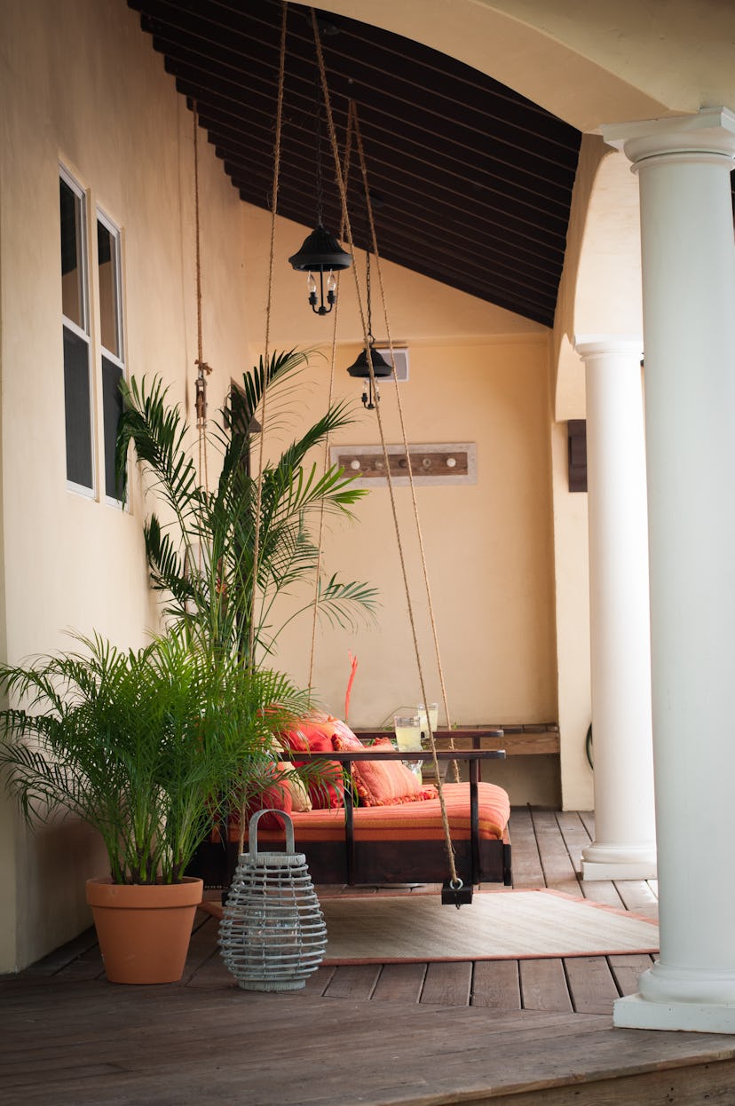 side view of orange upholstered swing chair on porch