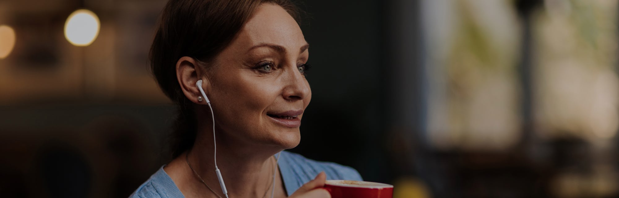 Beautiful brunette woman listening to music while having a coffee in her favourite shop