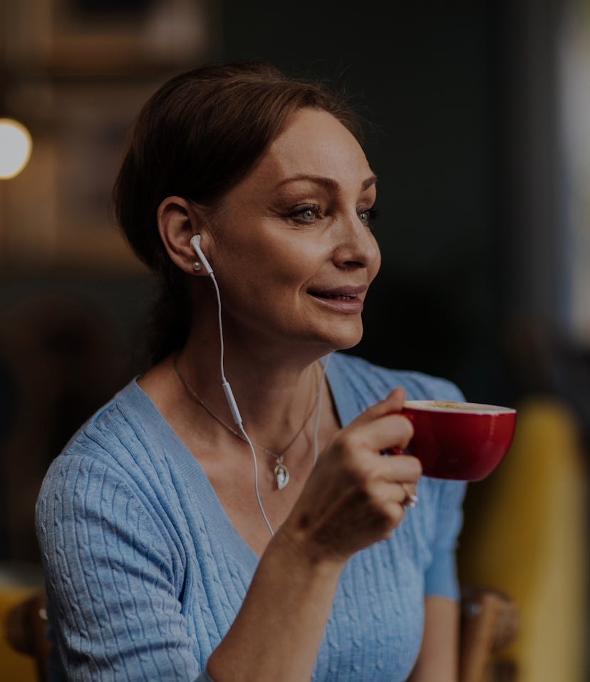 Beautiful brunette woman listening to music while having a coffee in her favourite shop