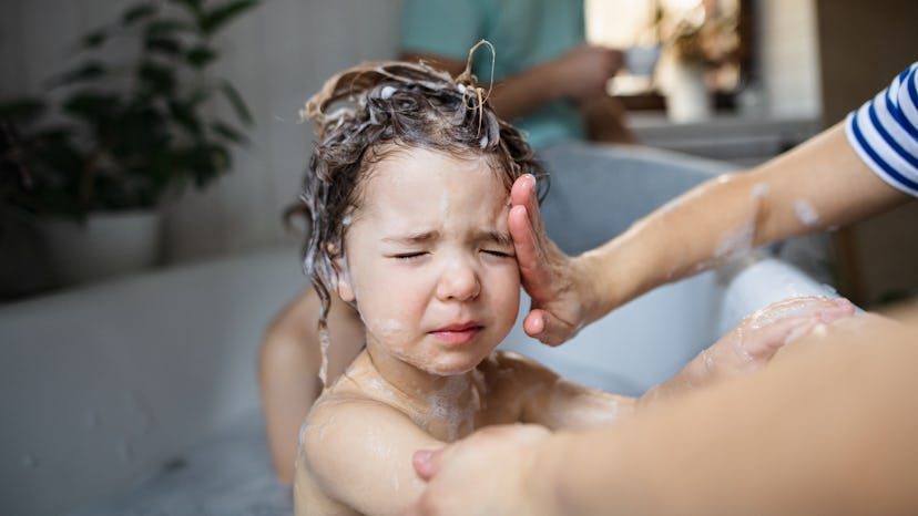 Lifestyle shot of adult shampoo washing a kid's hair in the bath tub.