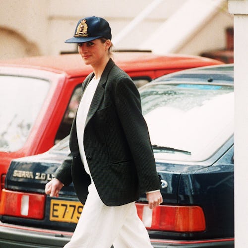 Princess Diana wearing an unusual combination of white trousers, boots, a blazer jacket and a baseba...