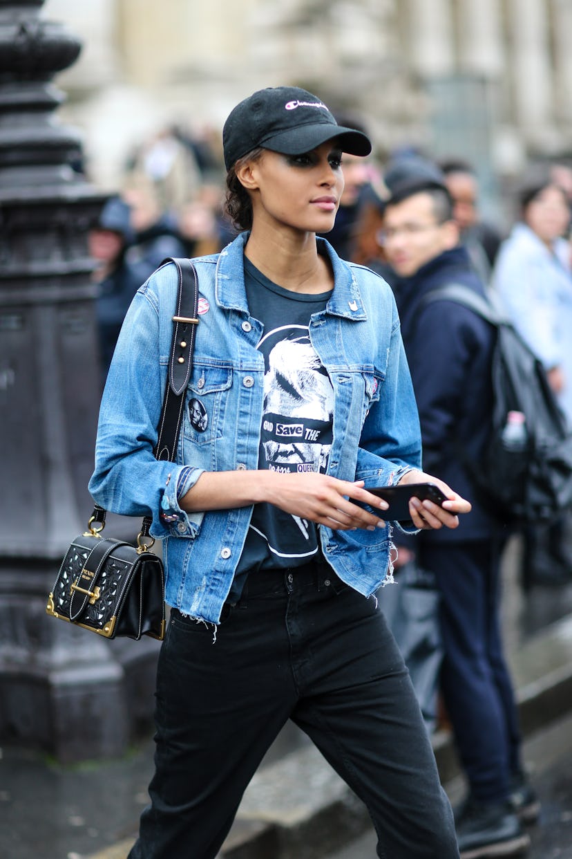 PARIS, FRANCE - MARCH 04:  Cindy Bruna wears a cap, a blue denim jacket, and a Prada bag, outside th...
