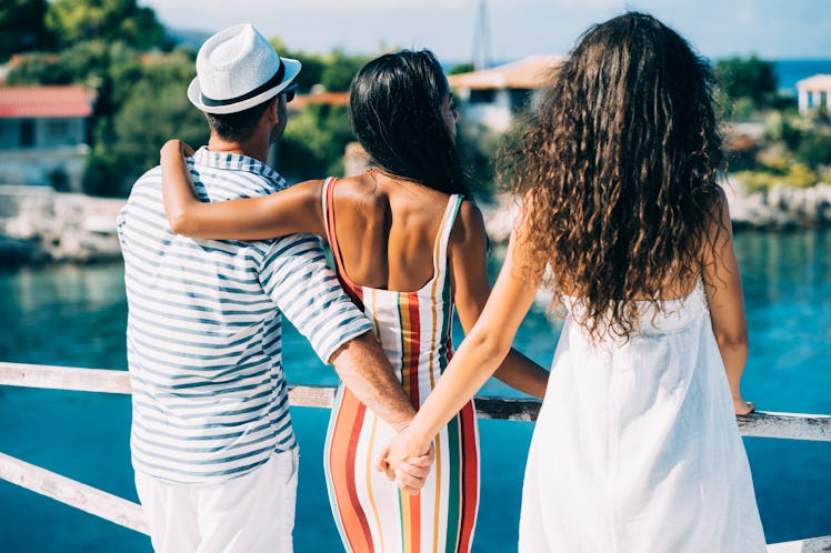 Couple in vacations standing on harbor, man hoding other woman's hand.