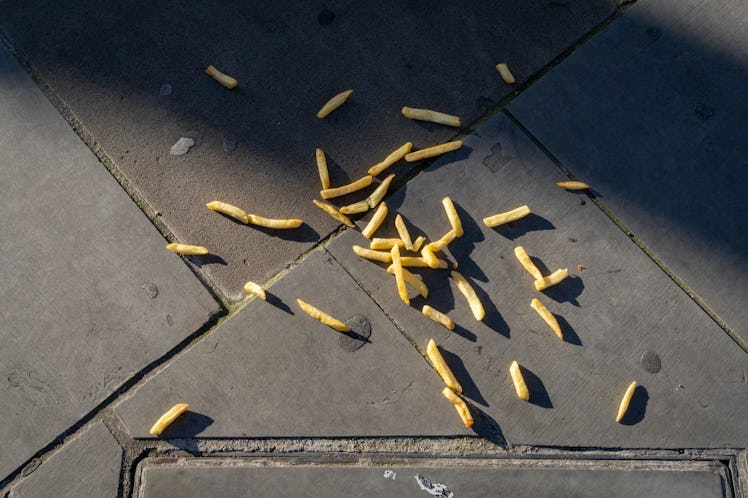 A detail of a spillage of dropped and discarded chips that are spread across the pavement in Shoredi...